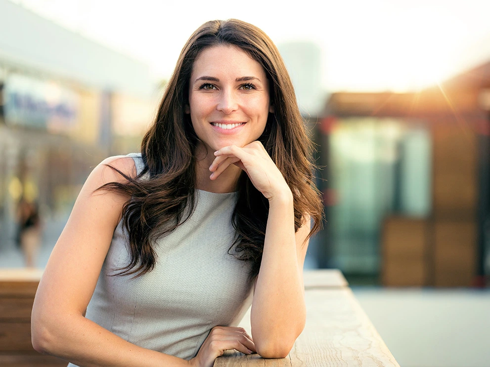 confident woman with a bright, healthy smile posing outdoors